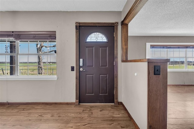 entrance foyer featuring baseboards, a textured ceiling, and wood finished floors