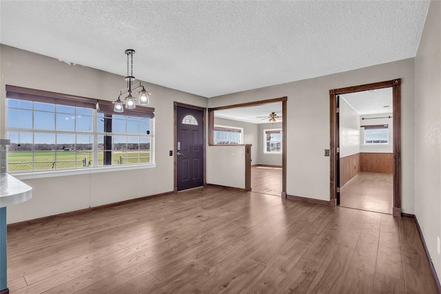 interior space with baseboards, a textured ceiling, and hardwood / wood-style floors