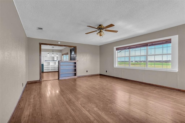 unfurnished living room with visible vents, baseboards, ceiling fan, a textured ceiling, and wood-type flooring