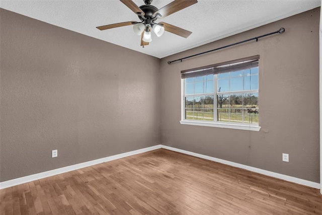 spare room with ceiling fan, a textured ceiling, baseboards, and wood finished floors