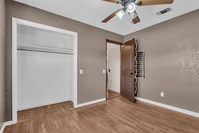 unfurnished bedroom featuring visible vents, ceiling fan, baseboards, wood finished floors, and a closet