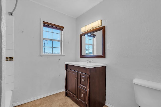 bathroom with baseboards, toilet, a healthy amount of sunlight, and vanity