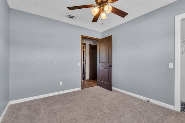 spare room featuring ceiling fan, carpet, visible vents, and baseboards