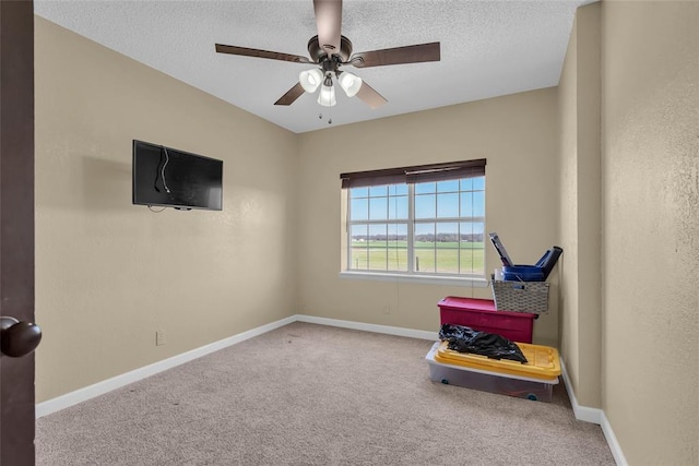 living area featuring baseboards, a textured ceiling, carpet, and a ceiling fan