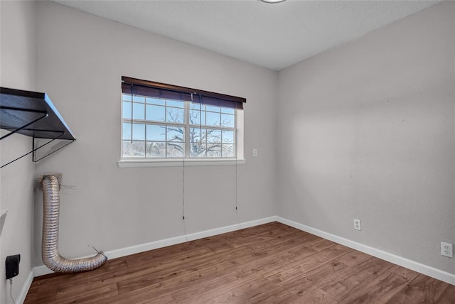 unfurnished room with baseboards, a textured ceiling, and wood finished floors