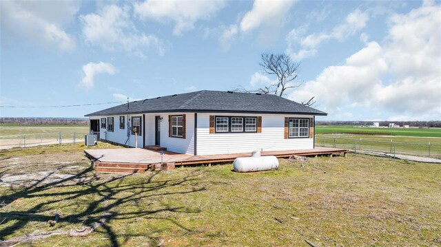 back of property with a rural view, fence, central air condition unit, a wooden deck, and a lawn