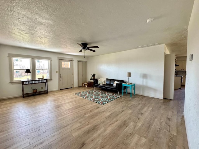 living room with visible vents, a textured ceiling, wood finished floors, and a ceiling fan