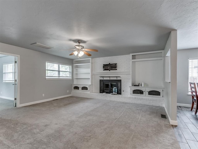 4303 N Redmond Ave, Bethany, OK 73008 - unfurnished living room featuring a ceiling fan, carpet flooring, a brick fireplace, built in features, and a textured ceiling