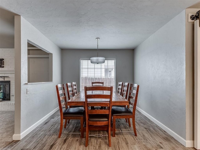 4303 N Redmond Ave, Bethany, OK 73008 - dining area featuring light wood-type flooring, a textured ceiling, and a brick fireplace