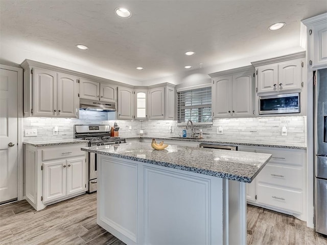 4303 N Redmond Ave, Bethany, OK 73008 - kitchen with appliances with stainless steel finishes, under cabinet range hood, decorative backsplash, light wood-type flooring, and recessed lighting