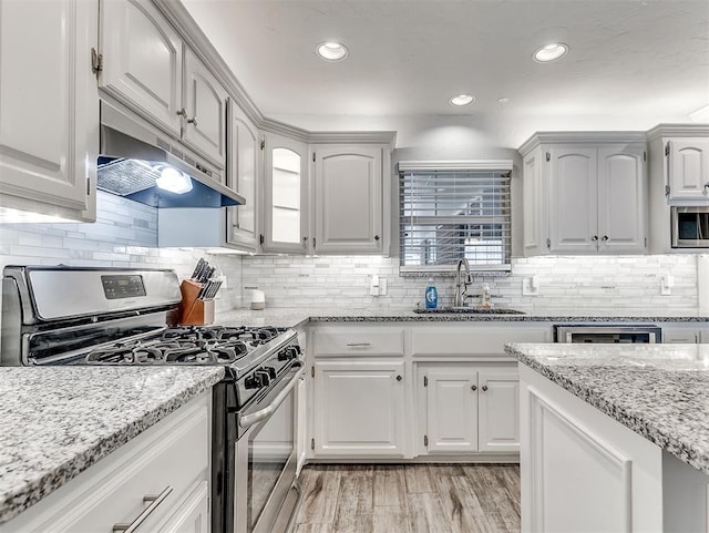 4303 N Redmond Ave, Bethany, OK 73008 - kitchen featuring stainless steel appliances, under cabinet range hood, light stone counters, recessed lighting, and backsplash