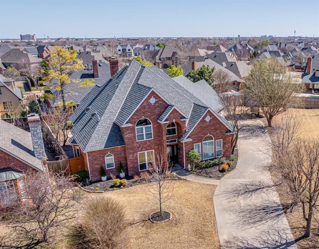 exterior space with a residential view, brick siding, a chimney, and a shingled roof