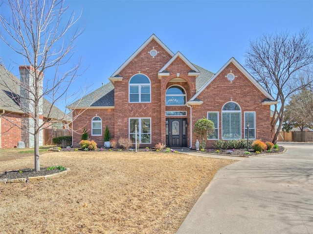 traditional-style home with a front yard, fence, and brick siding