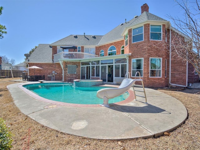 view of pool with a pool with connected hot tub, a water slide, fence, a sunroom, and a patio