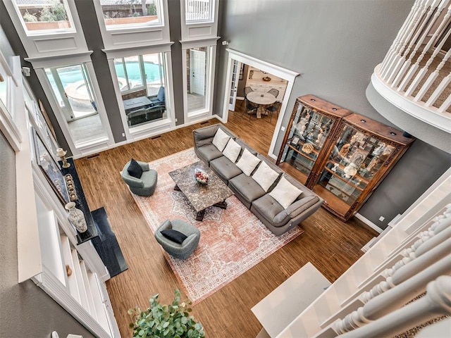 living area featuring visible vents, wood finished floors, and a towering ceiling