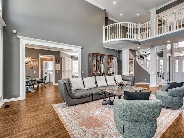 living room with visible vents, crown molding, stairs, decorative columns, and wood finished floors