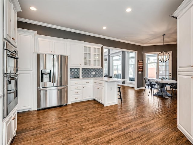 kitchen featuring a peninsula, appliances with stainless steel finishes, a breakfast bar area, and white cabinetry