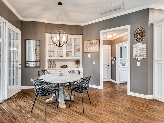 dining area featuring visible vents, wood finished floors, crown molding, baseboards, and a chandelier