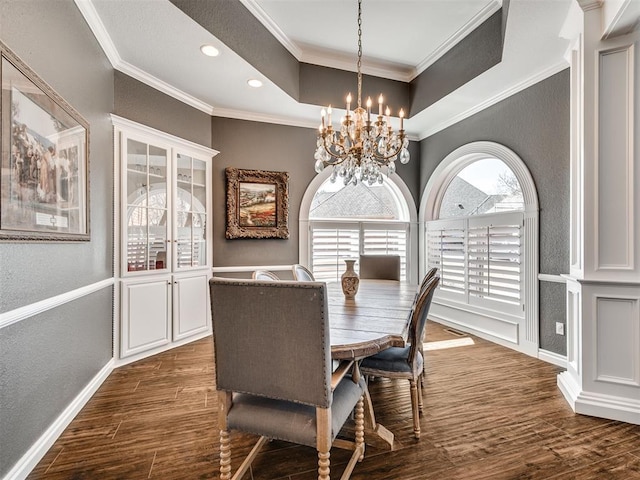 dining space featuring dark wood-style floors, baseboards, an inviting chandelier, crown molding, and a raised ceiling