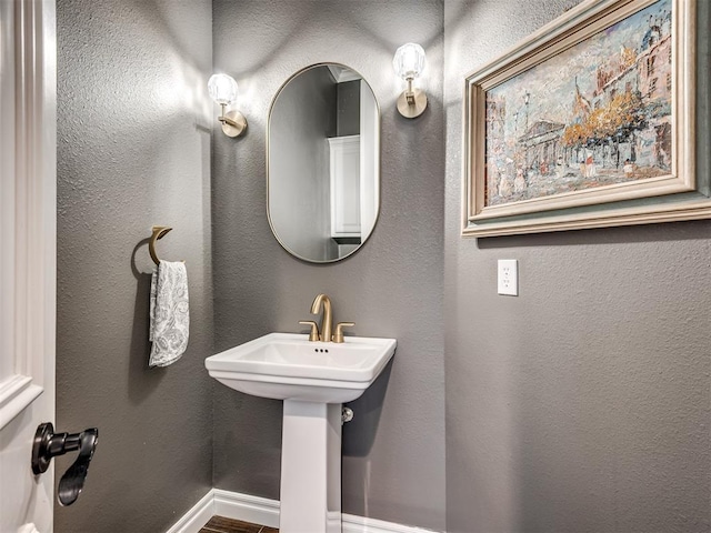 bathroom with a sink, baseboards, and a textured wall