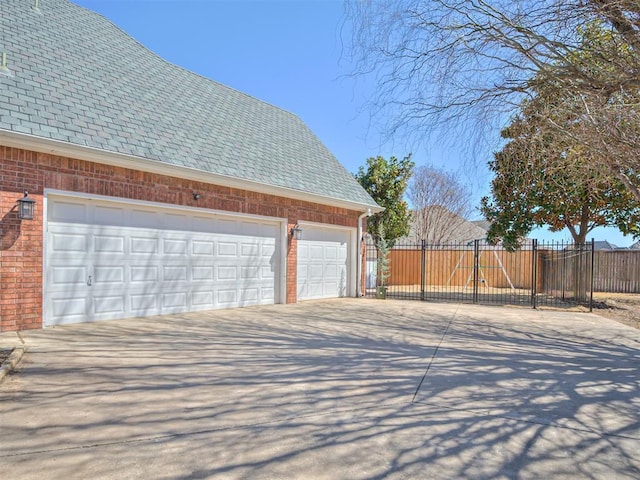 garage featuring concrete driveway and fence