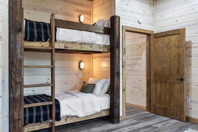 bedroom with wood finished floors and wood walls