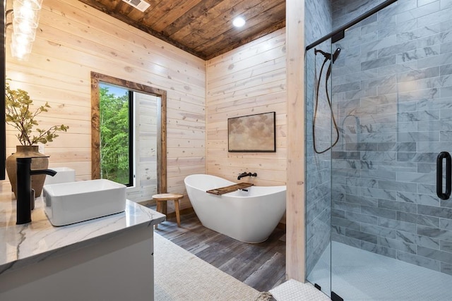 bathroom with a shower stall, a freestanding bath, wood ceiling, and wood walls