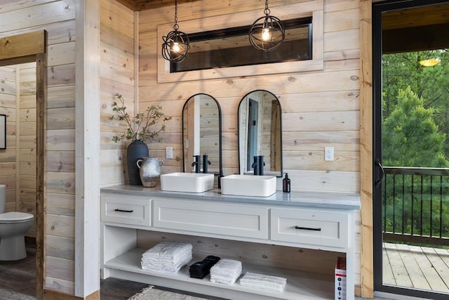 bathroom with wooden walls, toilet, and vanity