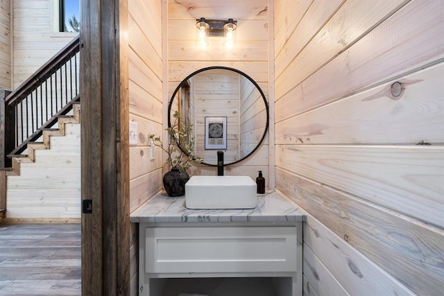 details featuring wooden walls, vanity, and wood finished floors