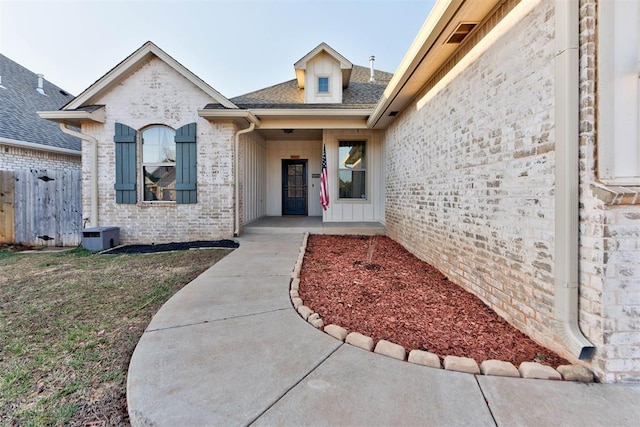 property entrance with brick siding and a shingled roof