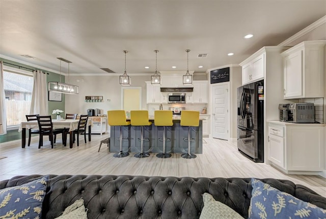 kitchen with stainless steel microwave, visible vents, open floor plan, a kitchen bar, and black refrigerator with ice dispenser