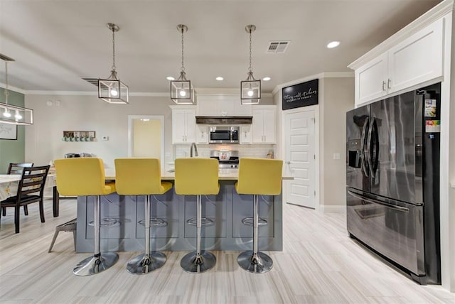 kitchen featuring stainless steel microwave, visible vents, decorative backsplash, black fridge, and white cabinets