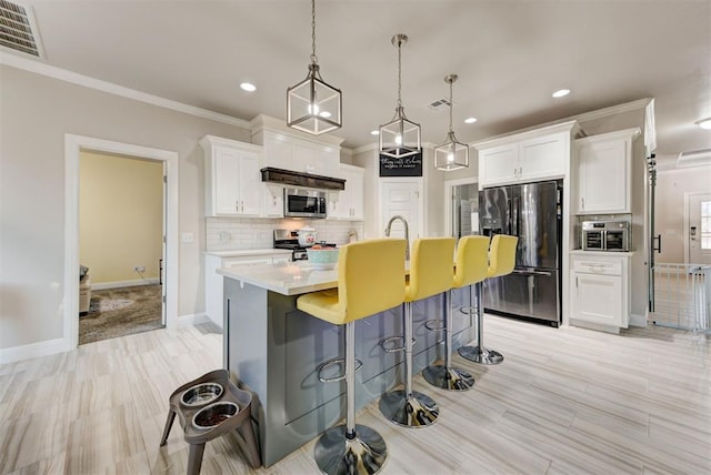 kitchen with a kitchen bar, tasteful backsplash, visible vents, and stainless steel appliances