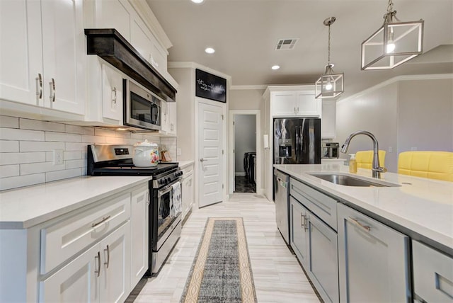 kitchen with visible vents, a sink, ornamental molding, light countertops, and stainless steel appliances