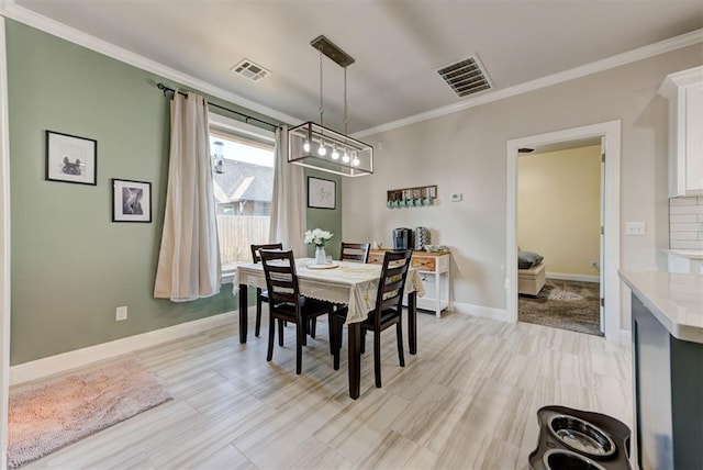 dining area with visible vents, baseboards, light wood-style floors, and crown molding