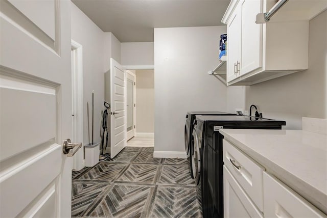 washroom with cabinet space, washer and dryer, and baseboards