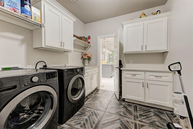 clothes washing area featuring cabinet space and washing machine and dryer