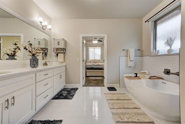 ensuite bathroom featuring double vanity, a freestanding bath, ensuite bath, and a sink