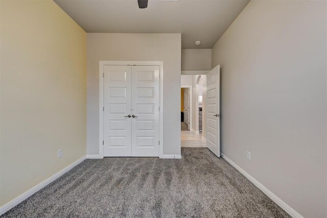 unfurnished bedroom featuring a closet, a ceiling fan, baseboards, and carpet floors