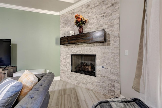 living area with baseboards, a stone fireplace, and crown molding