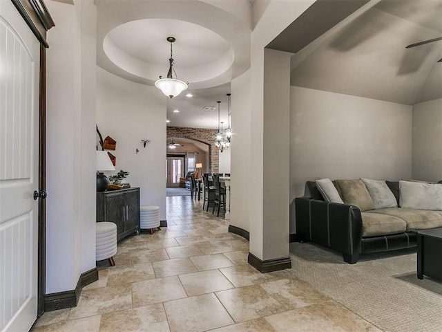 interior space with a raised ceiling, baseboards, and arched walkways