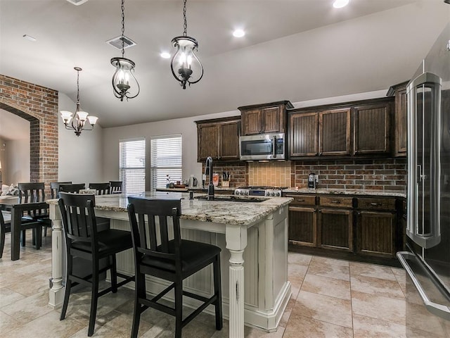 kitchen featuring fridge with ice dispenser, visible vents, light stone counters, stainless steel microwave, and arched walkways