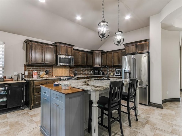 kitchen featuring pendant lighting, an island with sink, decorative backsplash, appliances with stainless steel finishes, and a sink