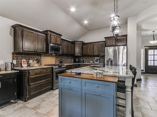 kitchen with a sink, stainless steel appliances, tasteful backsplash, and vaulted ceiling