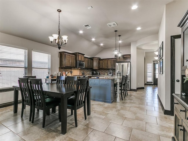 dining area featuring a chandelier, visible vents, baseboards, and lofted ceiling