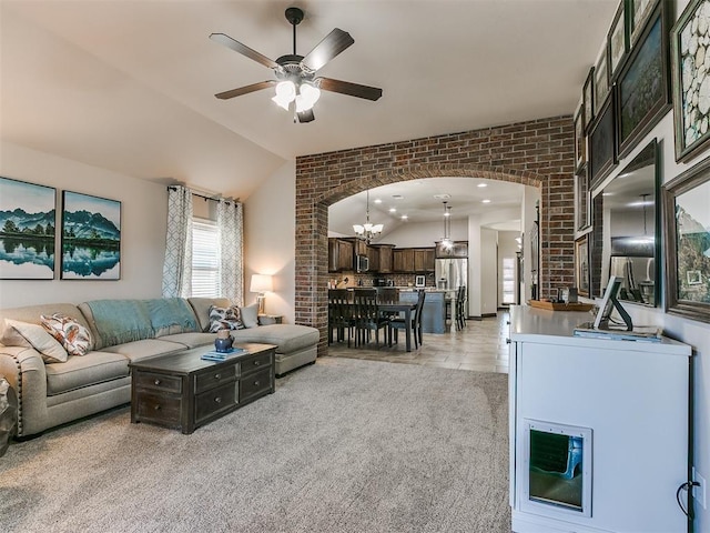 living room featuring arched walkways, ceiling fan with notable chandelier, brick wall, and vaulted ceiling