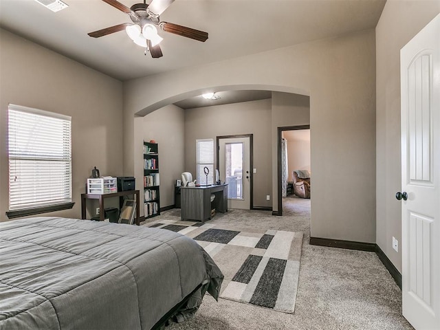 bedroom with arched walkways, light colored carpet, baseboards, and ceiling fan