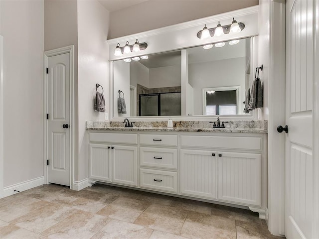 full bath with double vanity, baseboards, a stall shower, and a sink