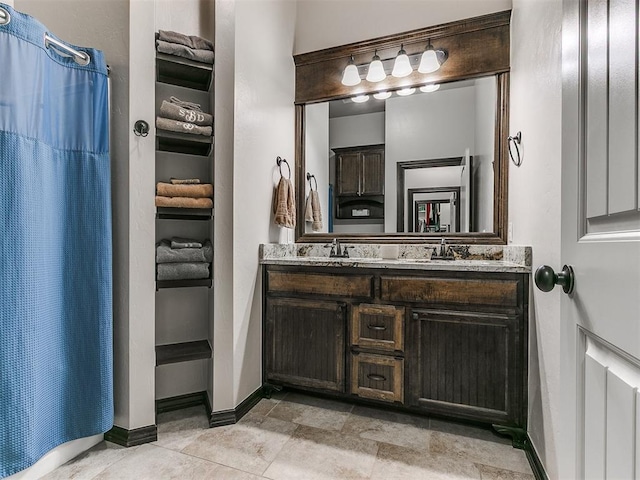 full bath featuring double vanity, baseboards, and a sink