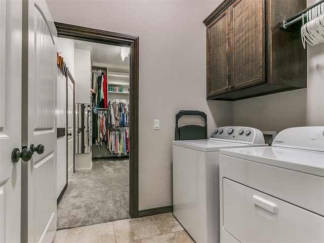 clothes washing area featuring washer and dryer, baseboards, cabinet space, and light colored carpet